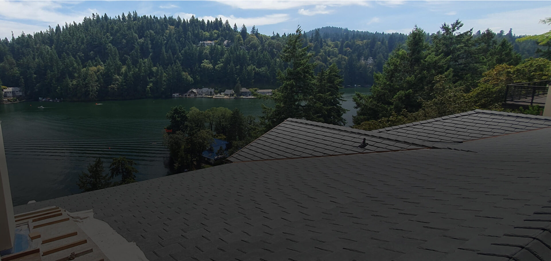 Residential roof with new asphalt shingles overlooking lake and forest