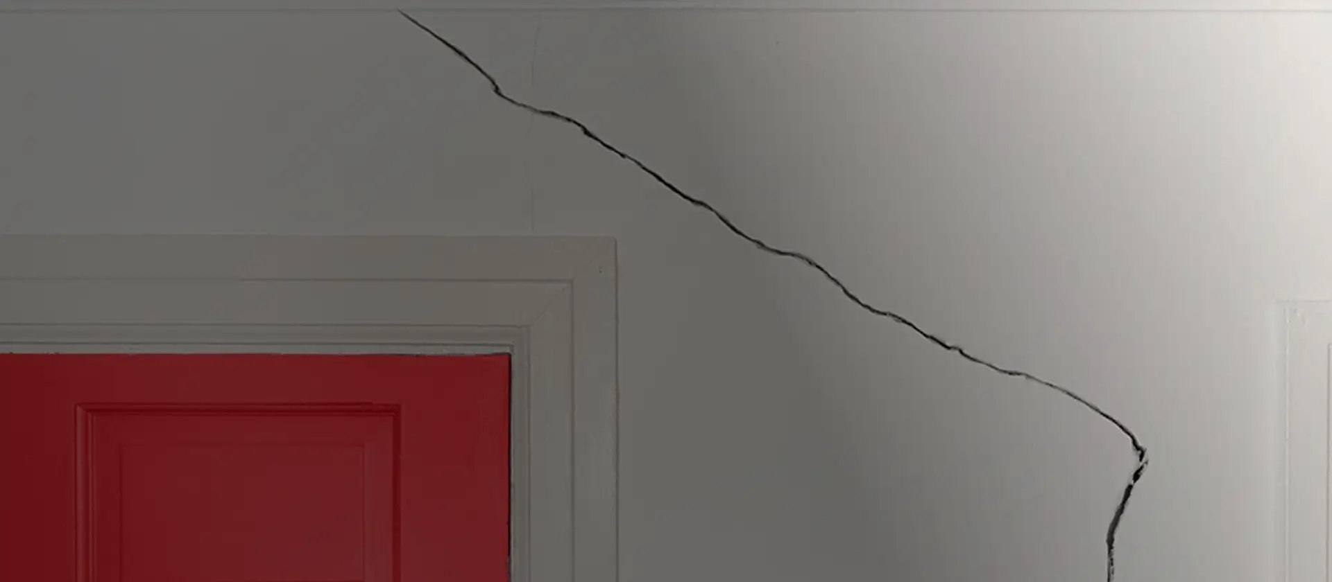 Large structural crack running across an interior wall above a doorway, showing signs of foundation movement and the need for professional structural repair