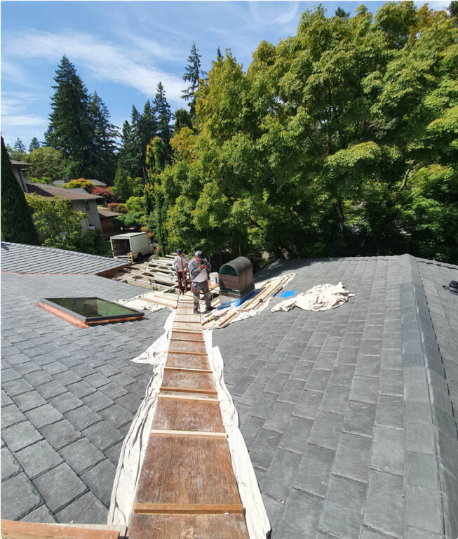 Roofing team working on slate roof with temporary walkway boards installed