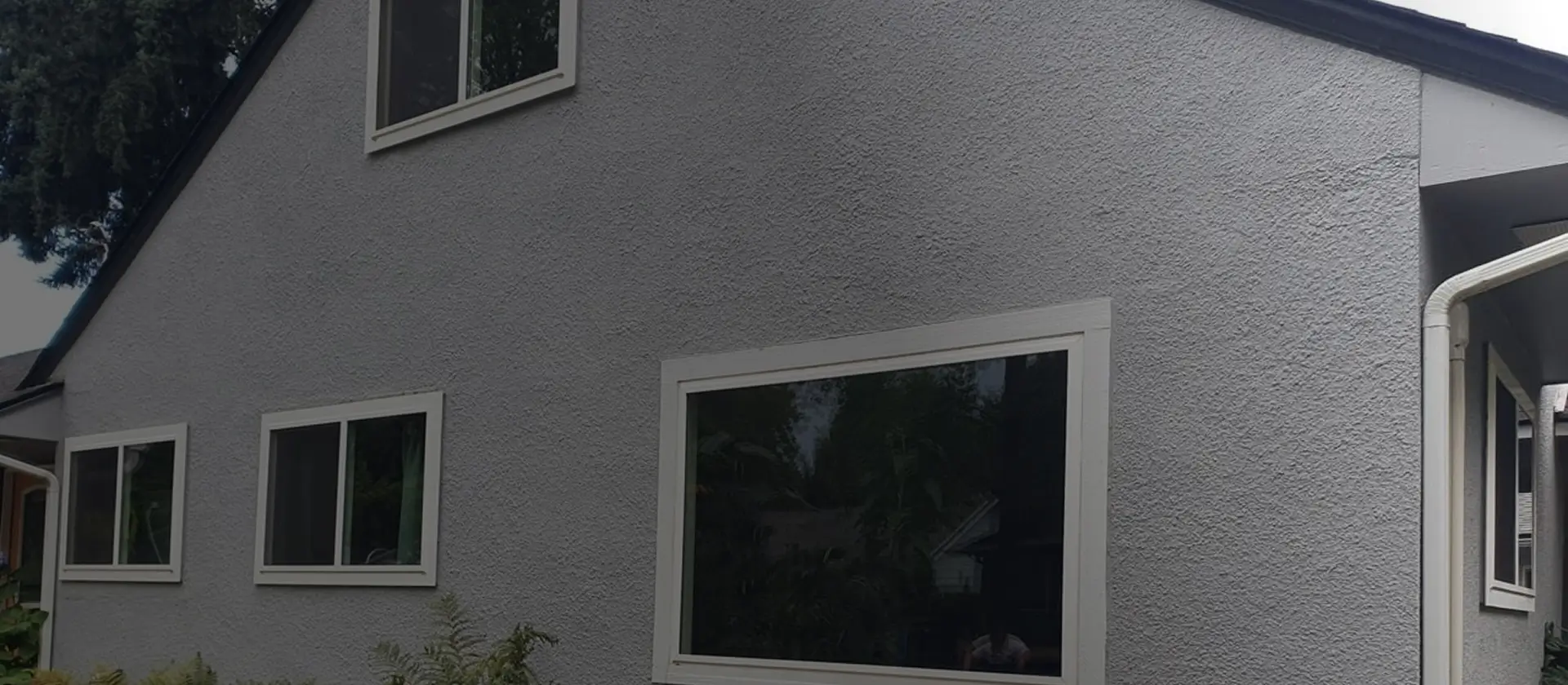 Home exterior with new windows and restored stucco siding, showing RainWise exterior repair, moisture protection, and window replacement services in Portland