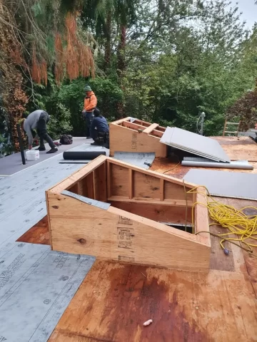 Roof repair project with exposed roof framing and underlayment installation, showing RainWise contractors rebuilding damaged roof decking and improving waterproofing