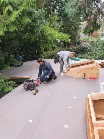 Roofing crew working on a flat roof installing skylight framing and waterproof underlayment, illustrating RainWise roof repair and moisture protection services