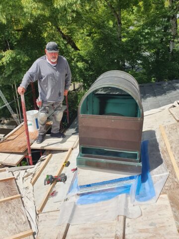 Technician working on a chimney rebuild with a copper hood and waterproofing membrane installation