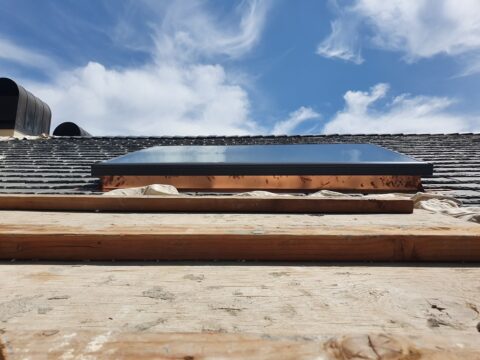 Low-angle photo of newly installed skylight with proper flashing and waterproofing on a residential roof