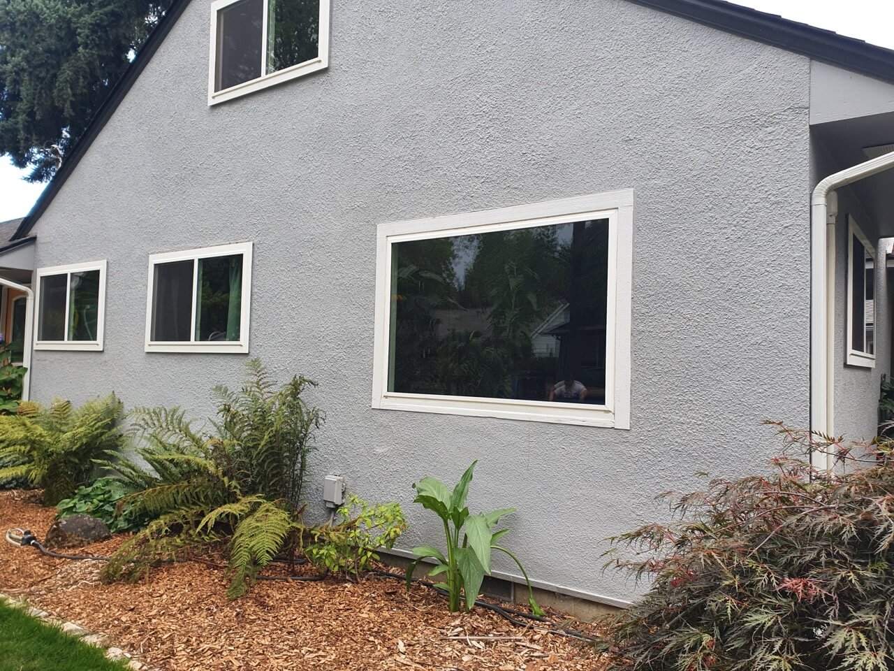 Home exterior after new window installation with restored stucco siding, demonstrating RainWise moisture protection and exterior repair services in Portland