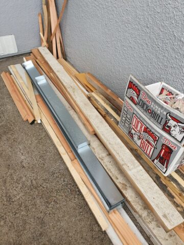 Construction materials including metal framing, lumber, and removed exterior components prepared for a siding replacement and structural repair project