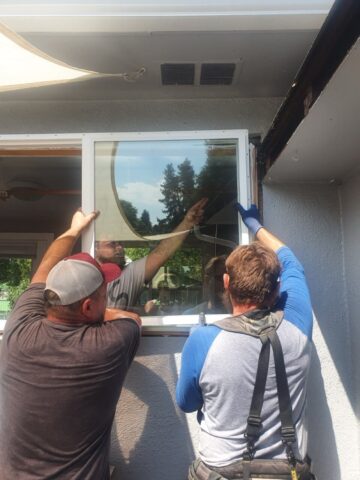 Contractors installing a new window frame on a home exterior, ensuring proper sealing and leak-proof flashing as part of RainWise window replacement services in Portland