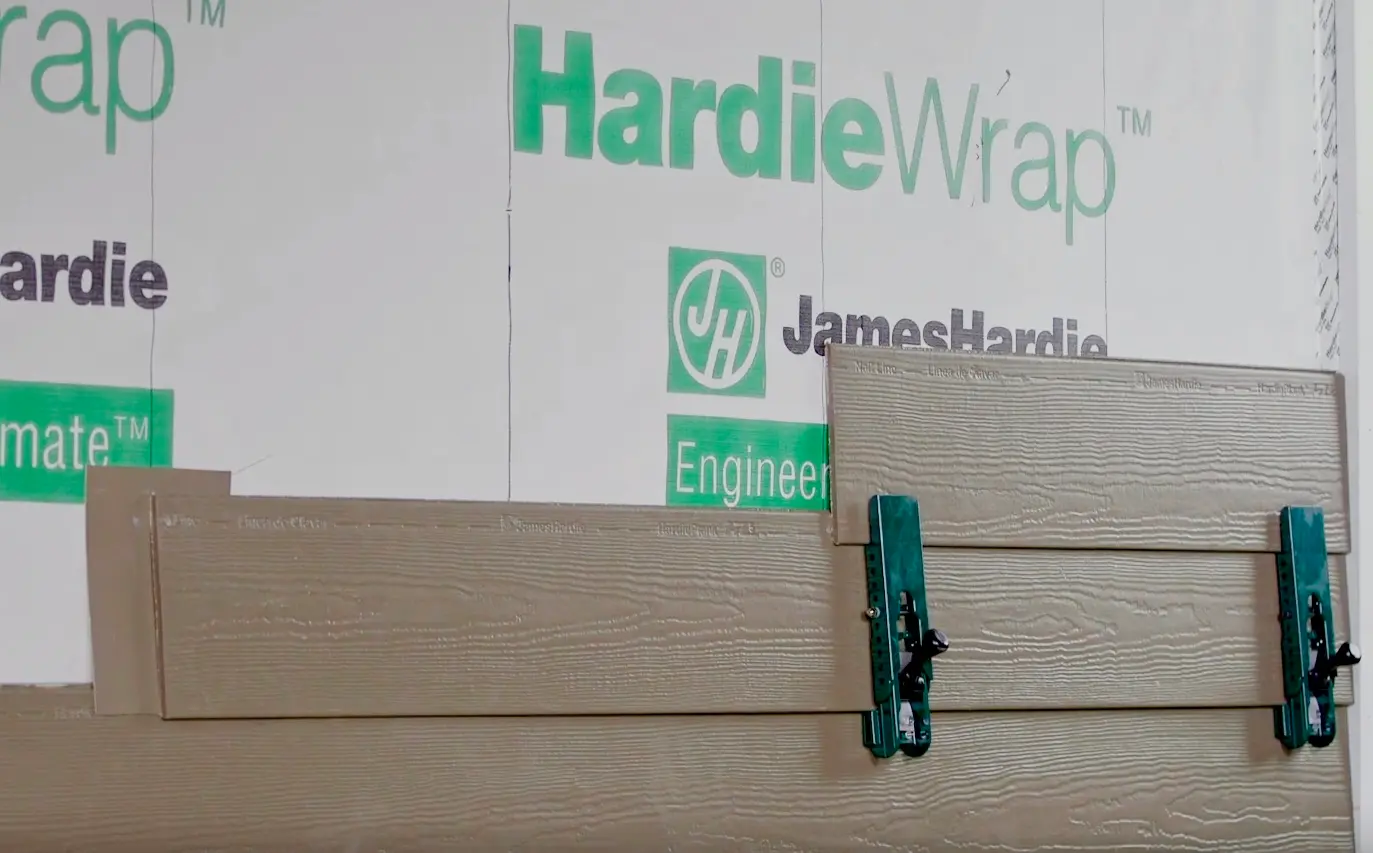 Close-up of James Hardie lap siding being installed over HardieWrap weather barrier, showing proper fiber cement siding installation and moisture protection